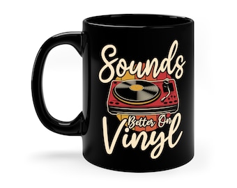 May include: Black ceramic mug featuring a retro illustration of a record player with the text "Sounds Better On Vinyl" in a vintage font. The record player is red and gold, set against a yellow and orange background.