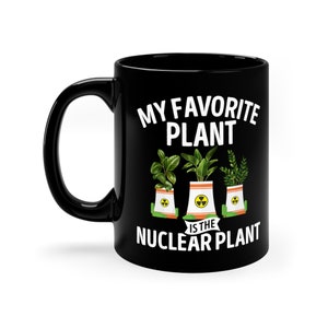 May include: Black coffee mug with a white design that says "My favorite plant is the nuclear plant". The design features three cartoon nuclear power plants with green plants growing out of the top.