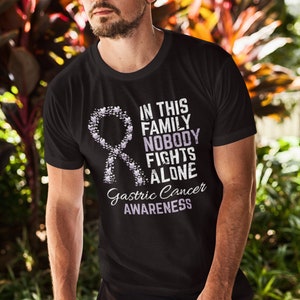 May include: A black t-shirt with a purple ribbon made of hearts and the text "In this family nobody fights alone. Gastric Cancer Awareness."