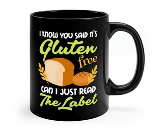 May include: Black coffee mug with a white design that says "I know you said it's gluten free can I just read the label". The design also includes a loaf of bread and a roll.