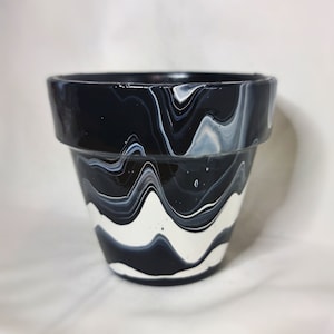 May include: Black and white marbled ceramic planter with a wavy design.