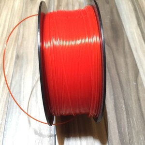 May include: A spool of bright red string trimmer line, wound around a black plastic spool.