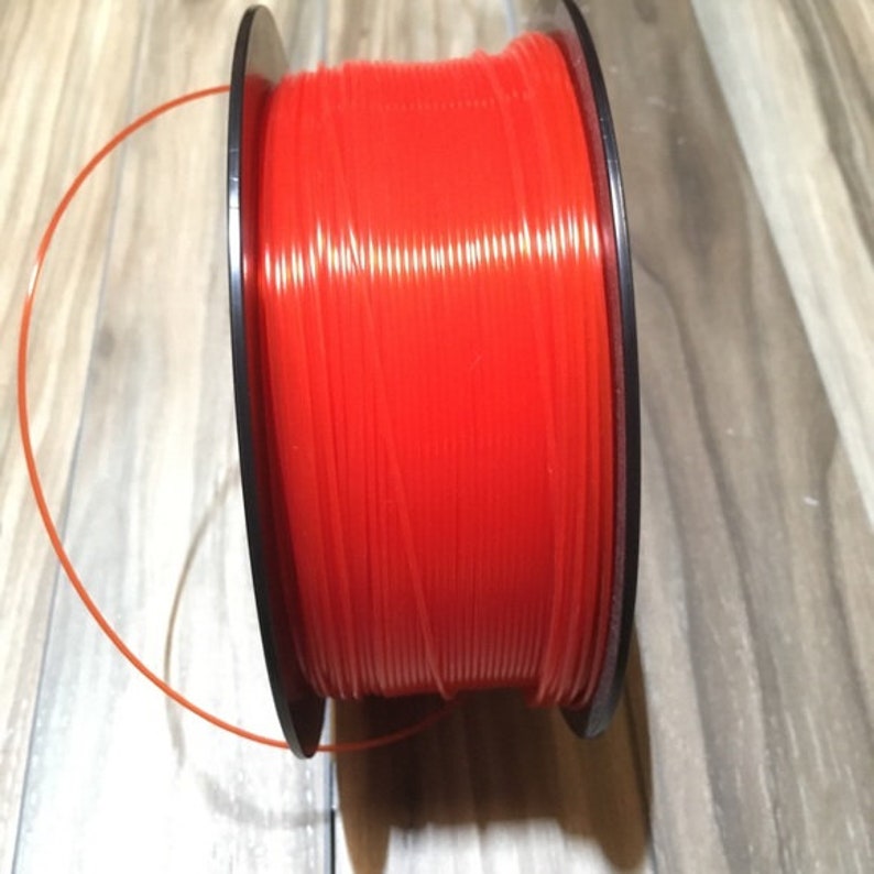 May include: A spool of bright red string trimmer line, wound around a black plastic spool.