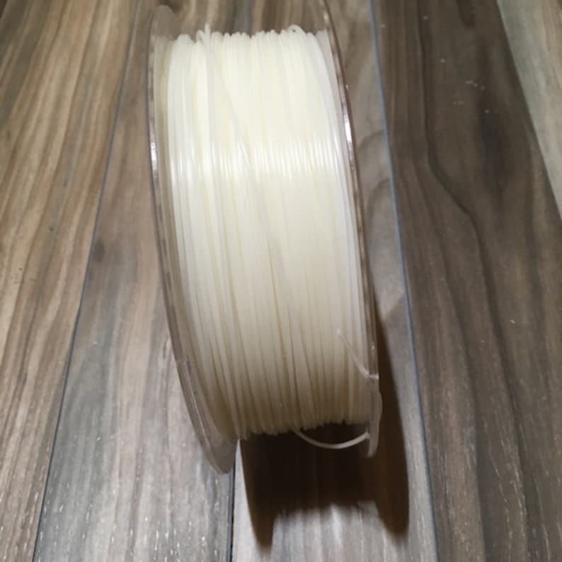 May include: A spool of clear white filament for 3D printing.