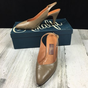 May include: A pair of light brown leather slingback heels with a pointed toe and a medium-height heel. The shoes are on a blue box with the word "Calf" printed on it.