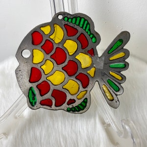 May include: A metal fish ornament with a red, yellow, and green stained glass design. The fish is made of metal and has a shiny finish.