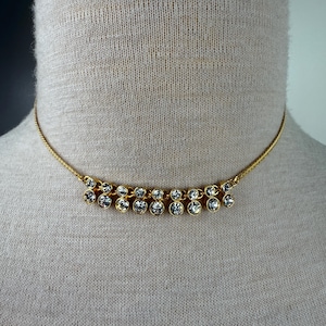 May include: A gold chain choker necklace with a row of clear rhinestone accents.