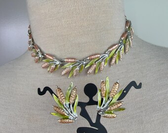 May include: A silver tone necklace and earrings set with green and pink enamel leaves. The jewelry is in a vintage style.