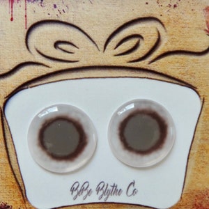 May include: Two brown and white Blythe doll eyes on a white card with the text "Blythe Blythe Co."