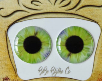 Puede incluir: Un par de ojos de muñeca verdes y amarillos con pupilas negras. Los ojos están sobre un fondo blanco con el texto "Baby Blythe Co."