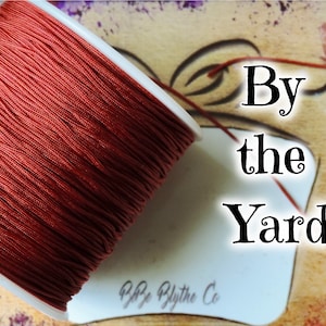 May include: A spool of red cord with the text "By the Yard" and "BBz Blythe Co" on a white label.