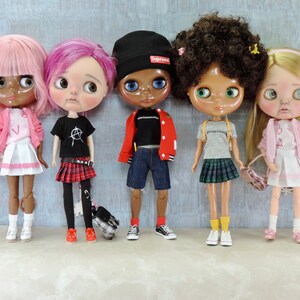May include: Five dolls with different hairstyles and outfits. The dolls are wearing a pink sweater and skirt, a black t-shirt and plaid skirt, a red jacket and blue jeans, a grey t-shirt and plaid skirt, and a pink sweater and skirt. The dolls are all holding small bags.