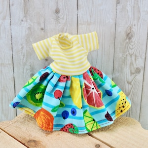 May include: A blue and yellow striped dress with a fruit print skirt. The skirt features a variety of fruits, including lemons, oranges, strawberries, and blueberries.