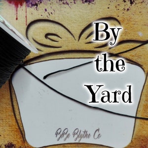 May include: A spool of black cord with the text "By the Yard" and "B&B Blythe Co." on a white background.