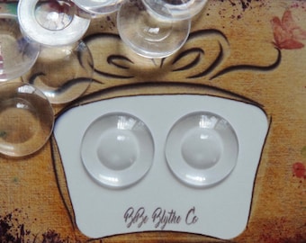 May include: Two clear glass eyes for Blythe dolls, set in a white mold with the text "Blythe Blythe Co."