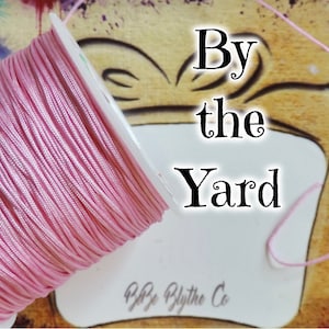 以下が含まれることがあります： 白いラベルに「By the Yard」と「P.P. Blythe Co.」の文字が書かれた、ピンク色のコードの糸巻き。