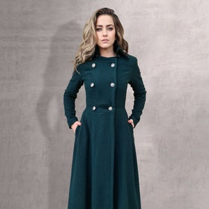 May include: A long, dark green coat with a double-breasted closure and a high collar. The coat has a fitted waist and a flared skirt.