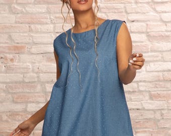 May include: A sleeveless, two-piece denim outfit. The top is a loose-fitting tunic with a round neckline and small white dots. The matching wide-leg pants also have white dots. The model is wearing red heels.