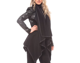 May include: A black leather jacket with a black scarf draped over the collar. The jacket has a long, asymmetrical hemline and a zipper closure. The model is wearing black pants and black heeled shoes.