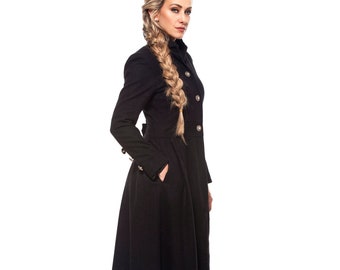 May include: A woman wearing a long black coat with a braided hairstyle. The coat has a high collar and a double-breasted closure.