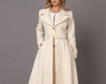 May include: A long, white coat with a wide belt and a high collar. The coat has a fitted bodice and a flowing skirt.