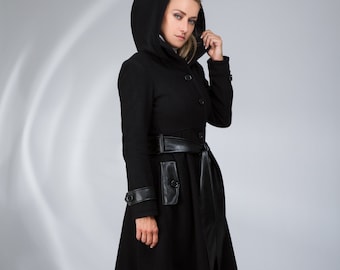 May include: A black hooded coat with a leather belt and a faux leather detail on the pocket. The coat has a fitted silhouette and a flared skirt.
