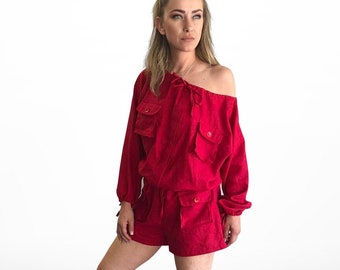 May include: A red off-the-shoulder jumpsuit with long sleeves and multiple pockets. The jumpsuit has a drawstring waist and is made of a soft, comfortable fabric.