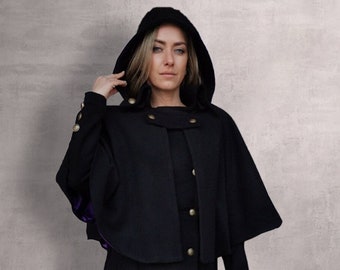 May include: A black hooded cape with gold buttons and a purple lining. The cape is long and flowing, and the hood is large and dramatic.