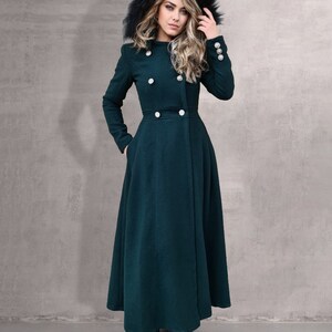 May include: A long, dark green coat with a black fur-lined hood. The coat has a double-breasted closure with silver buttons and a flared skirt.
