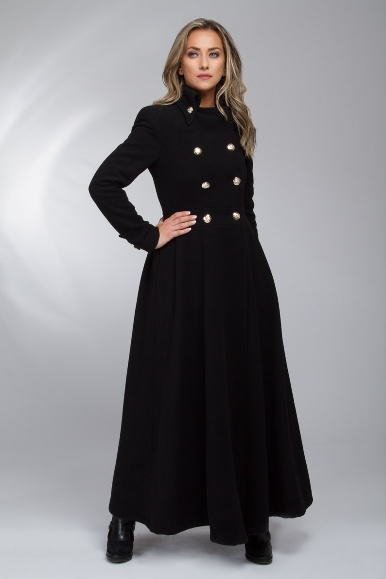 May include: A long black coat with a high collar and gold buttons. The coat has a flared skirt and is worn by a woman.