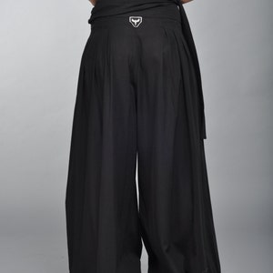 May include: Black wide-leg pants with a black fabric belt and a white logo on the back.