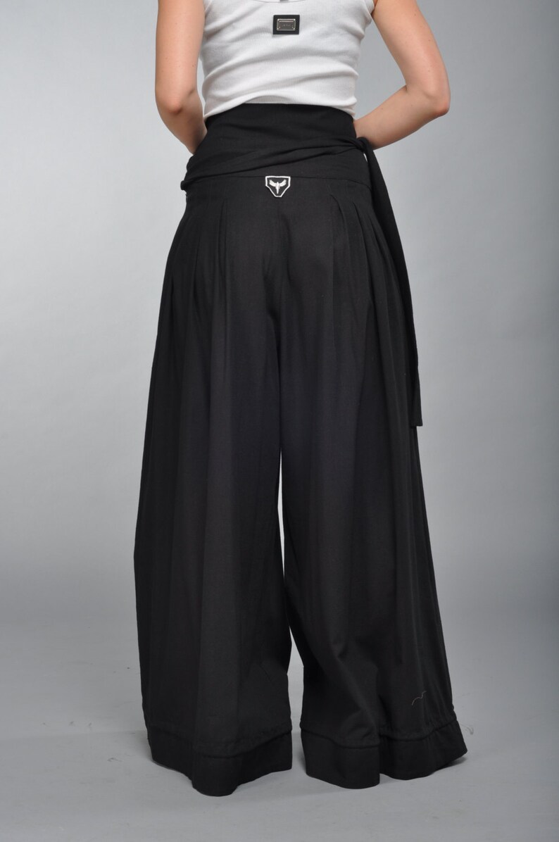 May include: Black wide-leg pants with a black fabric belt and a white logo on the back.