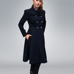 May include: A long black coat with a double breasted closure and a high collar. The coat has a flared skirt and is worn with black pants and black heels.
