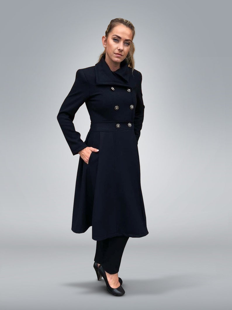 May include: A long black coat with a double breasted closure and a high collar. The coat has a flared skirt and is worn with black pants and black heels.