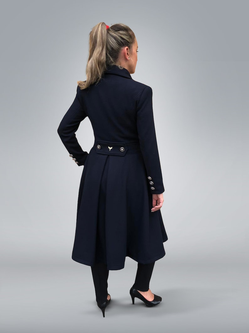 May include: A navy blue coat with a flared skirt and gold buttons. The coat has a high collar and a belt at the waist.