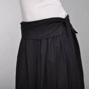 May include: A black skirt with a wide waistband that ties at the front. The skirt is made of a soft, flowing fabric.