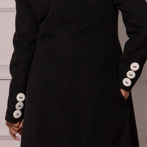 May include: Black long-sleeved coat with white buttons on the cuffs.