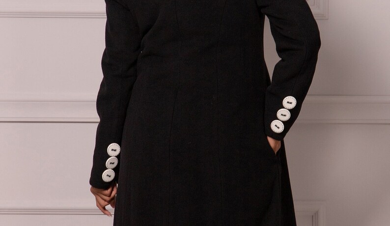 May include: Black long-sleeved coat with white buttons on the cuffs.