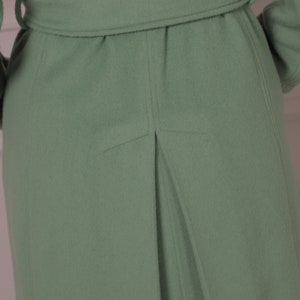 May include: A sage green coat with a belt and a single back pleat.