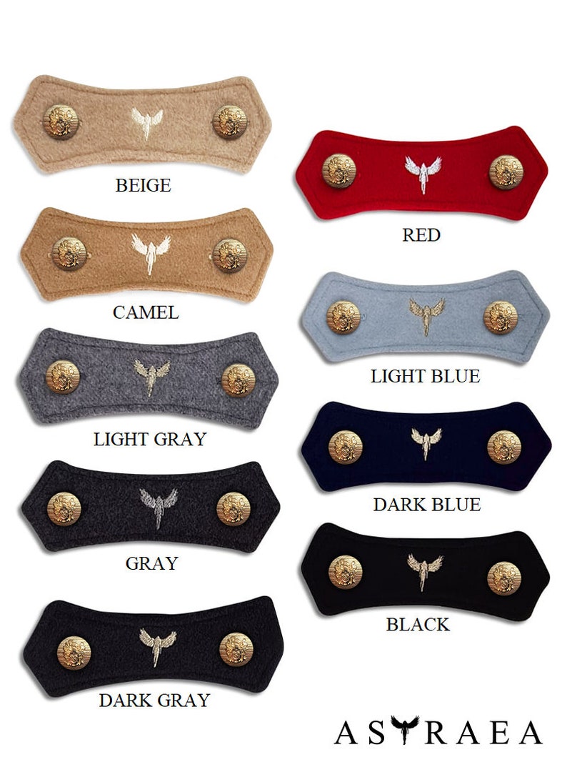 May include: Eight felt fabric mask extenders with gold-tone metal buttons. The extenders are in the colors beige, camel, red, light blue, light gray, gray, dark gray, and black. Each extender has a white embroidered angel wing design.