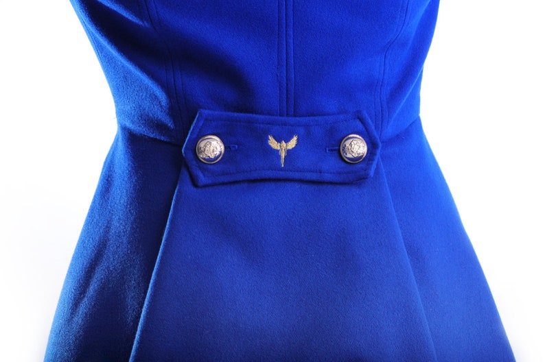 May include: A royal blue coat with a gold embroidered design and two gold buttons.