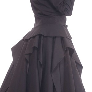 May include: A black dress with a ruffled skirt and a fitted bodice. The dress has a long, flowing skirt with multiple layers of ruffles.