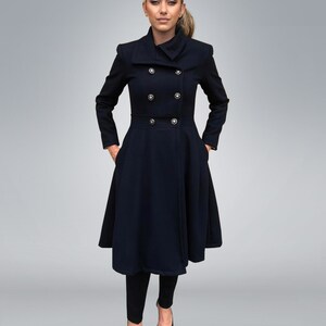 May include: A navy blue double-breasted coat with a high collar and a flared skirt. The coat has gold buttons and is worn by a woman with a ponytail.