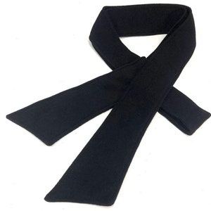 May include: A black fleece neck warmer with a long, narrow shape. It is designed to be worn around the neck for warmth.