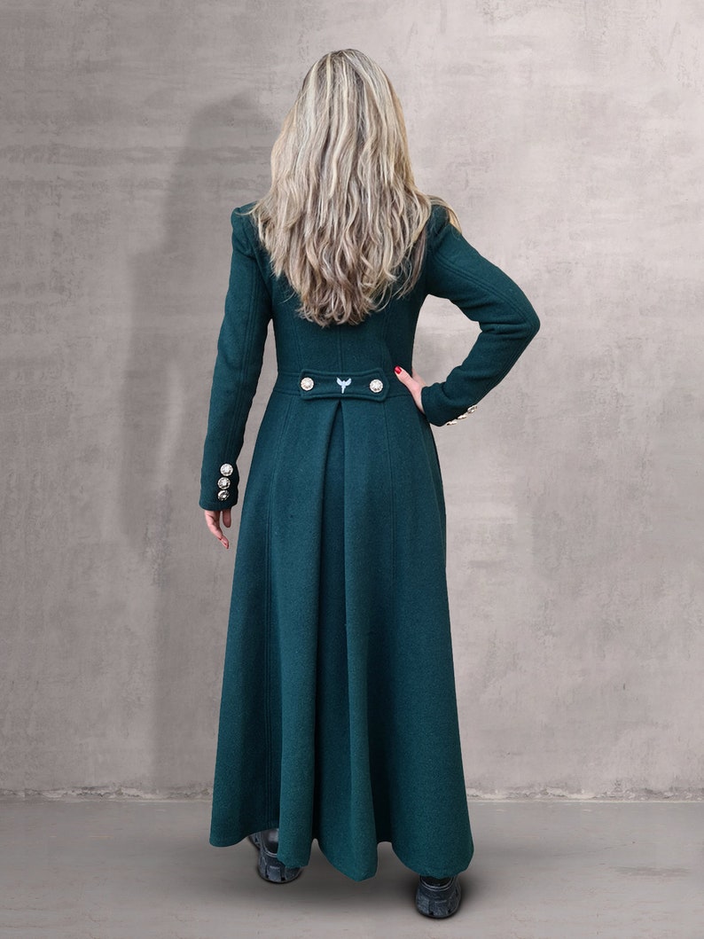 May include: A long, dark green coat with a high collar and gold buttons. The coat has a fitted bodice and a flowing skirt.