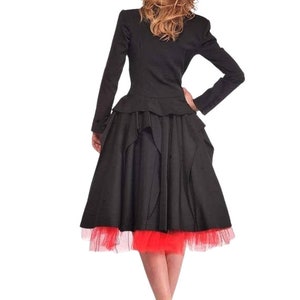 May include: A black jacket with a peplum hem and a black skirt with a red tulle underskirt. The person is wearing red high heels.