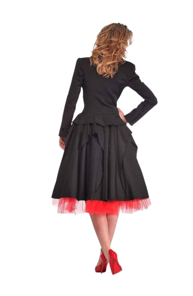 May include: A black jacket with a peplum hem and a black skirt with a red tulle underskirt. The person is wearing red high heels.