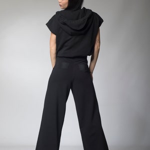 Puede incluir: Una sudadera negra con capucha y mangas cortas y pantalones negros de pierna ancha a juego. La sudadera tiene una capucha con cord&oacute;n y los pantalones tienen un bolsillo de parche en la parte posterior.