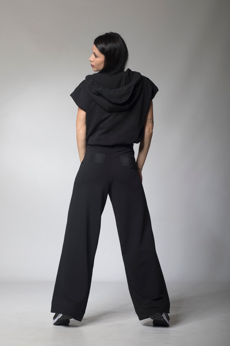 Puede incluir: Una sudadera negra con capucha y mangas cortas y pantalones negros de pierna ancha a juego. La sudadera tiene una capucha con cord&oacute;n y los pantalones tienen un bolsillo de parche en la parte posterior.