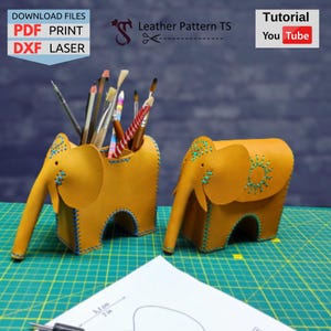 Puede incluir: Dos porta lápices de cuero amarillo en forma de elefante con costuras azules. El porta lápices de la izquierda tiene un montón de pinceles dentro. El porta lápices de la derecha tiene un diseño de sol en el lateral. La imagen incluye el texto "Leather Pattern TS" y "Download Files: PDF PRINT DXF LASER".